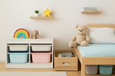 A well-organized children's room with light wood and pastel tones. A white storage unit with colorful bins (blue, pink, and white) holds various items. Above the unit, there are playful decorations, including a rainbow,